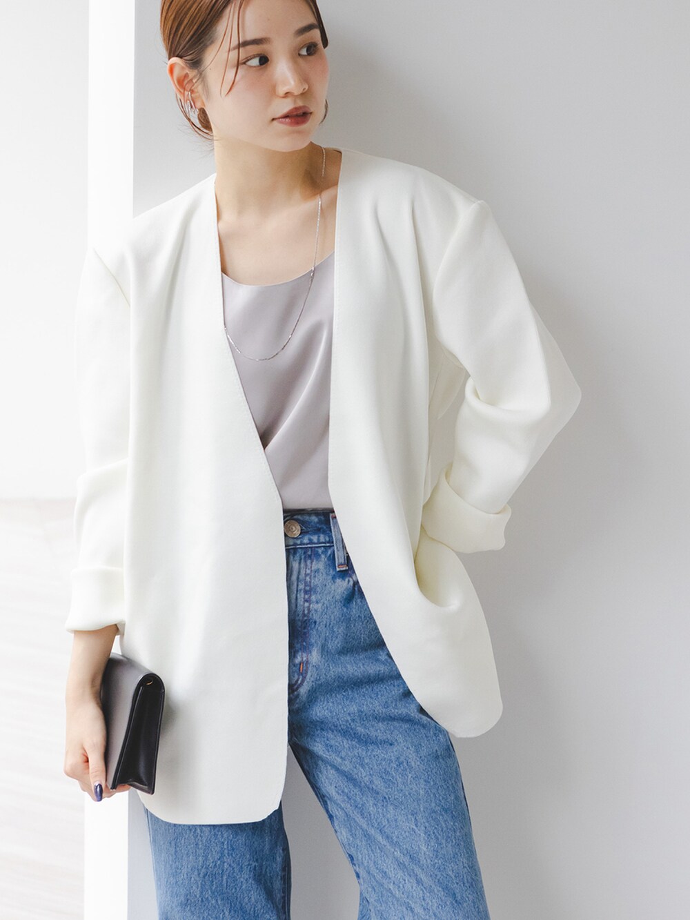 グレー系のタンクトップ、ホワイト系のカーディガン/ボレロ、ブルー系のデニムパンツを着用したレディースの秋コーディネートの3枚目の写真