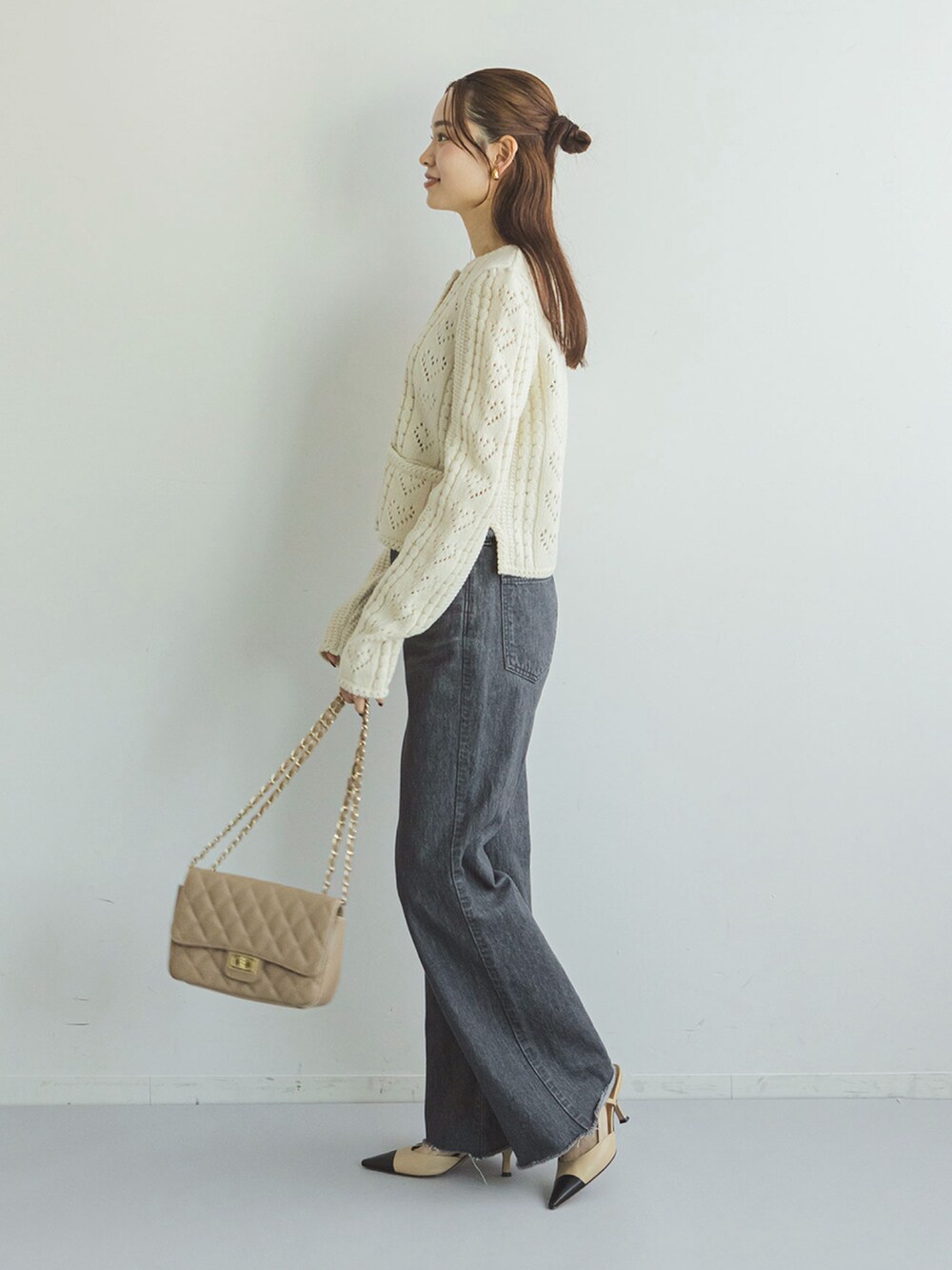 ホワイト系のカーディガン/ボレロ、ブラック系のデニムパンツ、ベージュ系のショルダーバッグを着用したレディースの秋コーディネートの2枚目の写真