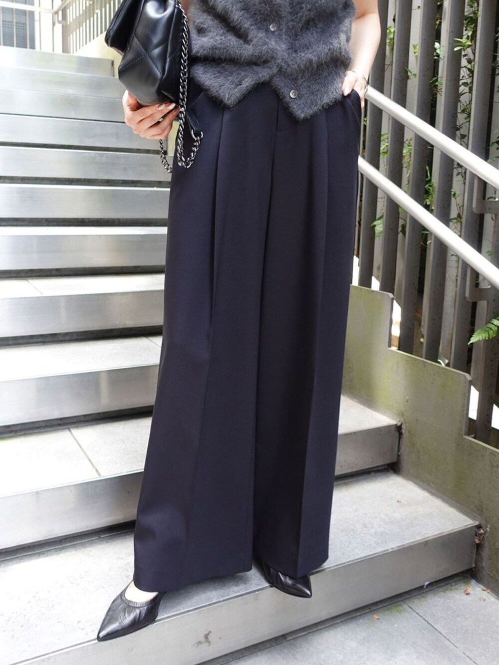 グレー系のベスト、ブルー系のスラックス、ブラック系のパンプスを着用したレディースの秋コーディネートの3枚目の写真