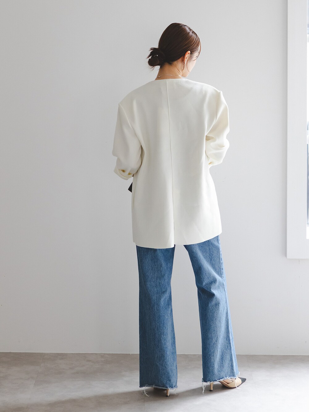グレー系のタンクトップ、ホワイト系のカーディガン/ボレロ、ブルー系のデニムパンツを着用したレディースの秋コーディネートの2枚目の写真