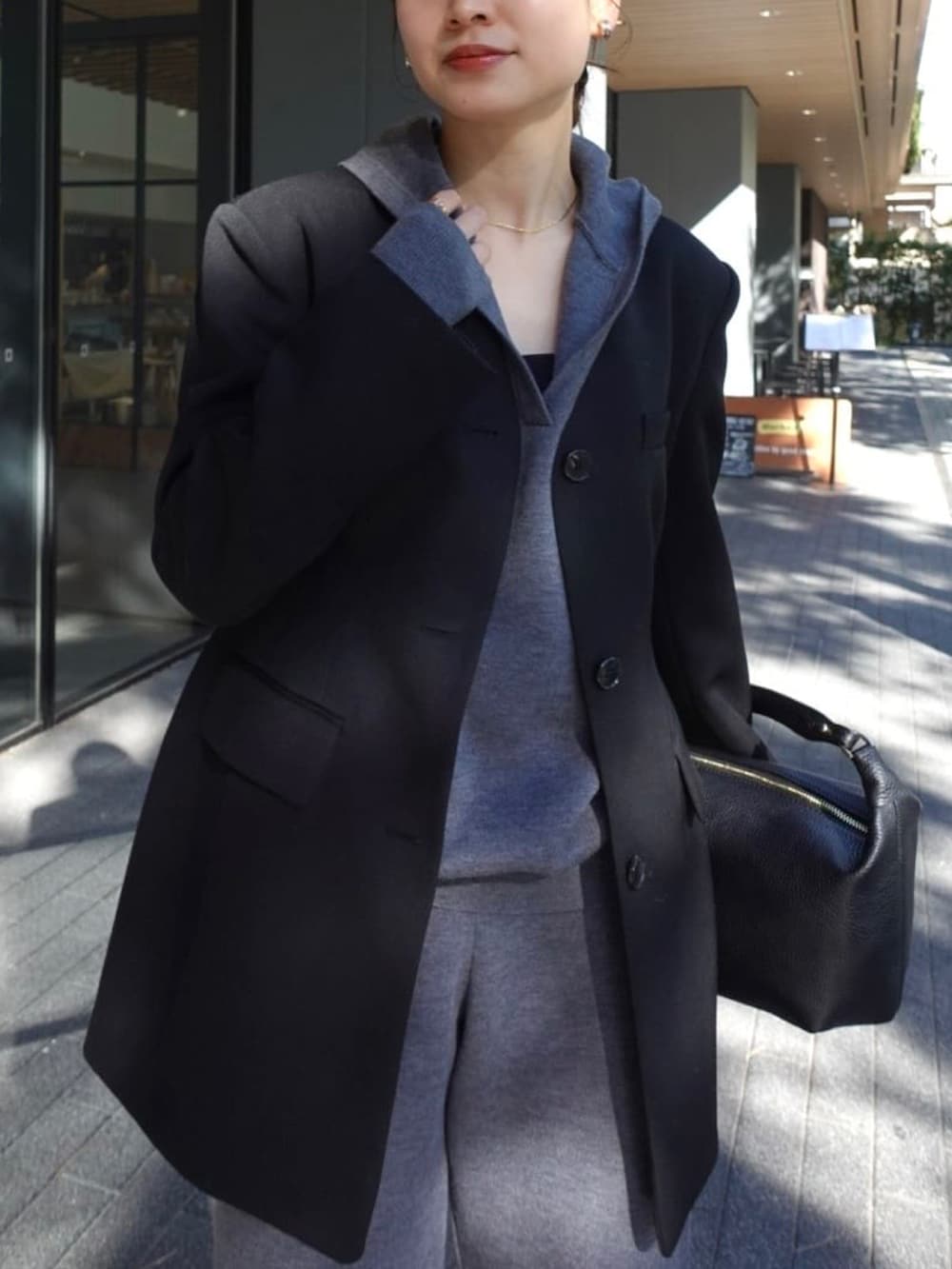 グレー系のニット/セーター、グレー系のスウェットパンツ、ブラック系のノーカラージャケットを着用したレディースの冬コーディネートの3枚目の写真