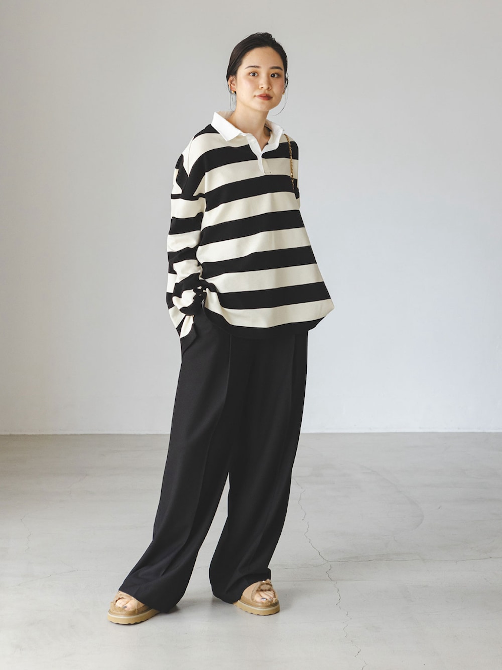 ホワイト系のTシャツ/カットソー、ブラック系のスラックス、ベージュ系のサンダルを着用したレディースの秋コーディネートの2枚目の写真