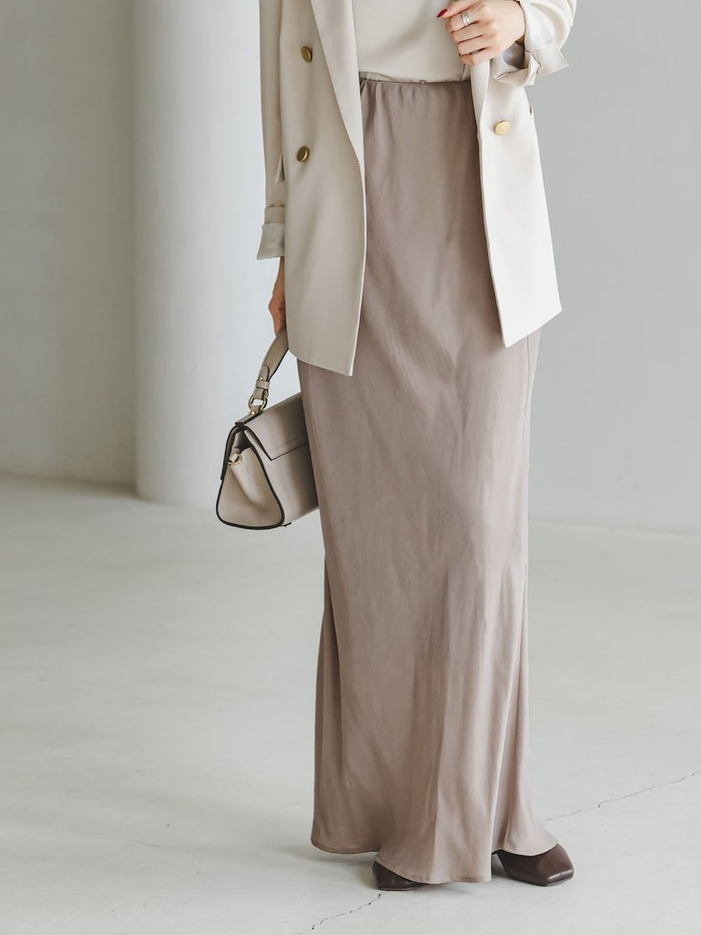 ベージュ系のテーラードジャケット、グレー系のスカート、ベージュ系のショルダーバッグを着用したレディースの秋コーディネートの3枚目の写真