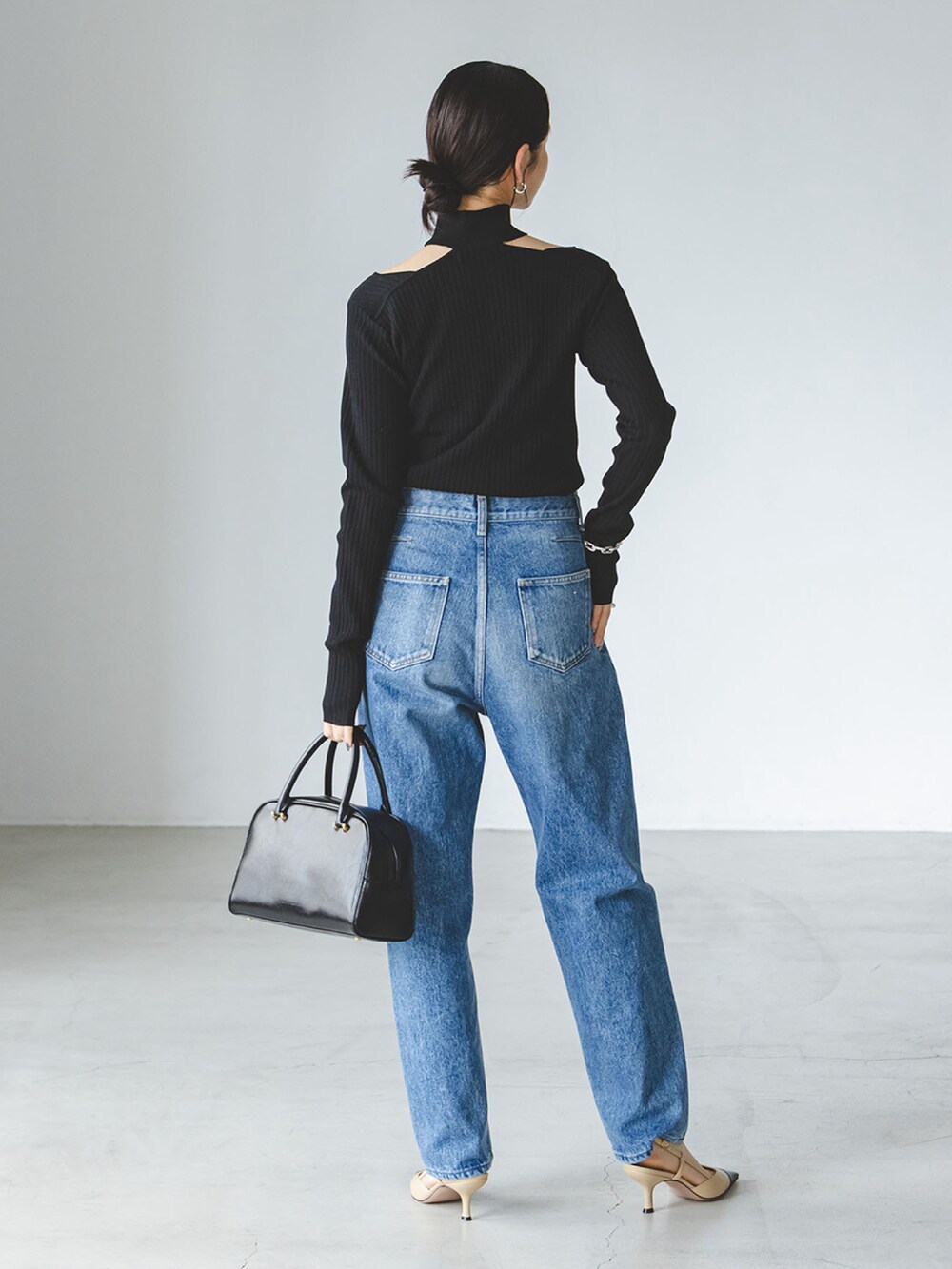 ブラック系のニット/セーター、ブルー系のデニムパンツを着用したレディースの夏コーディネートの2枚目の写真