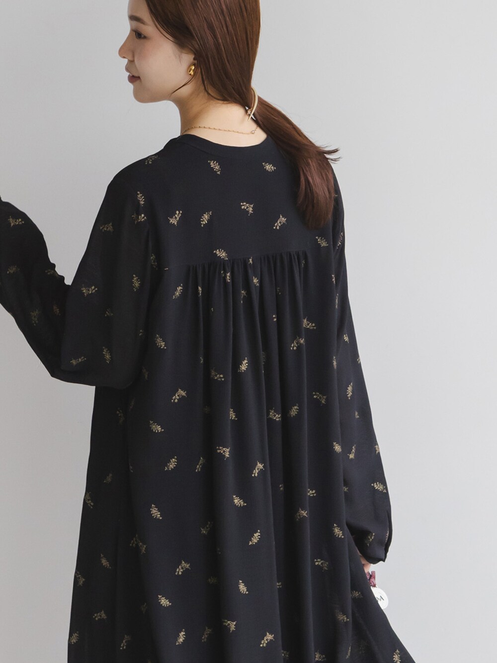 ブラック系のワンピース、レッド系のハンドバッグ、ブラック系のブーツを着用したレディースの冬コーディネートの4枚目の写真