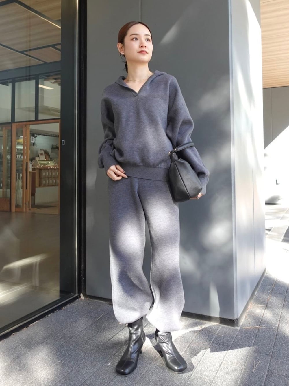 グレー系のニット/セーター、グレー系のスウェットパンツ、ブラック系のノーカラージャケットを着用したレディースの冬コーディネートの2枚目の写真