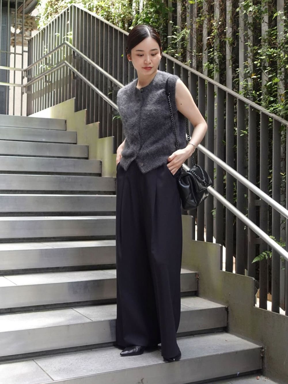 グレー系のベスト、ブルー系のスラックス、ブラック系のパンプスを着用したレディースの秋コーディネートの2枚目の写真