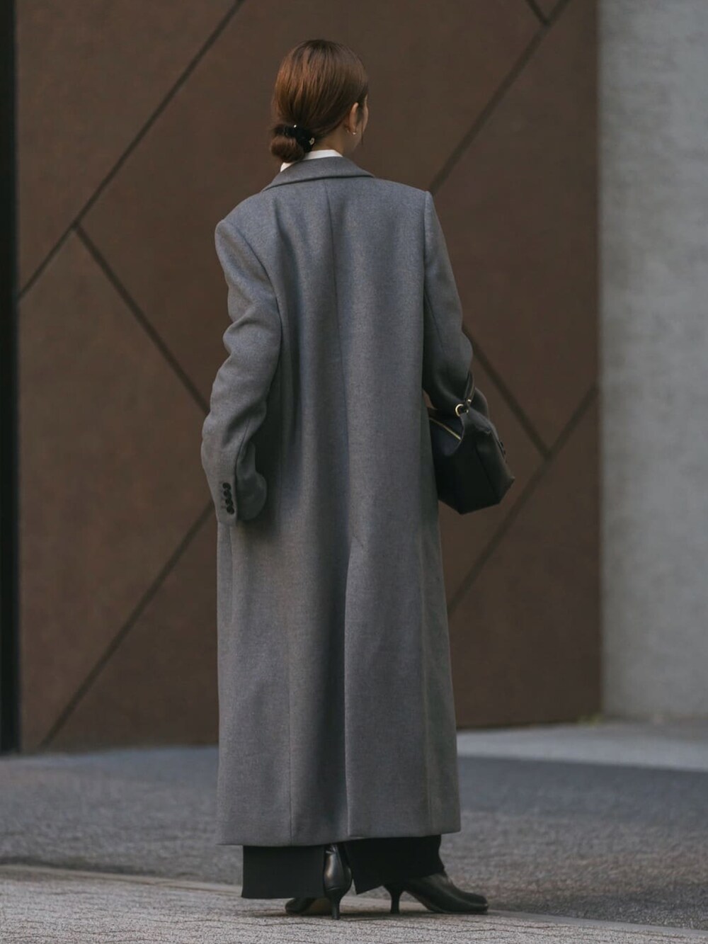 グレー系のチェスターコート、グレー系のTシャツ/カットソー、ブラック系のショルダーバッグを着用したレディースの冬コーディネートの3枚目の写真