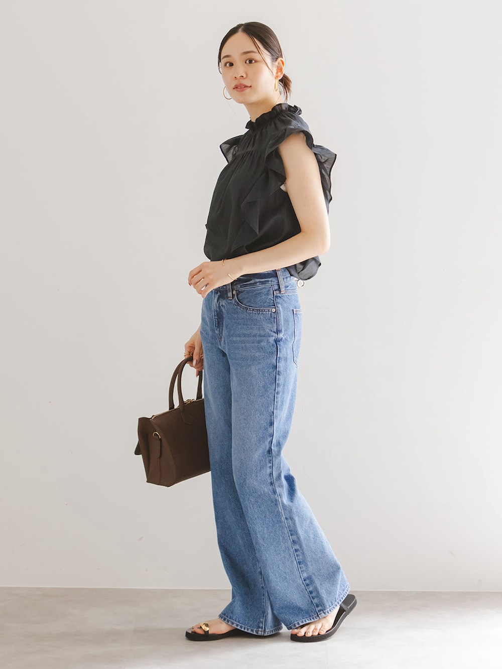 ブラック系のシャツ/ブラウス、ブルー系のデニムパンツ、ブラウン系のボストンバッグを着用したレディースの夏コーディネートの2枚目の写真