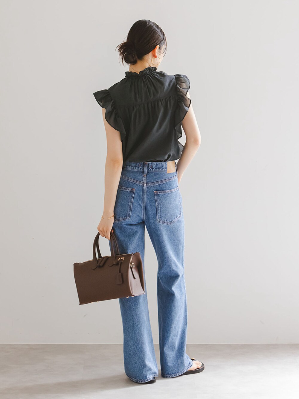 ブラック系のシャツ/ブラウス、ブルー系のデニムパンツ、ブラウン系のボストンバッグを着用したレディースの夏コーディネートの3枚目の写真