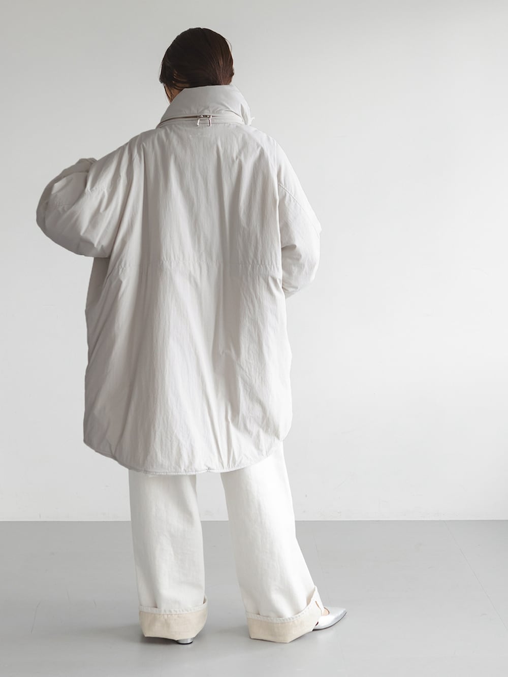 ホワイト系のダウンジャケット/コート、グレー系のニット/セーター、ホワイト系のデニムパンツを着用したレディースの秋コーディネートの3枚目の写真