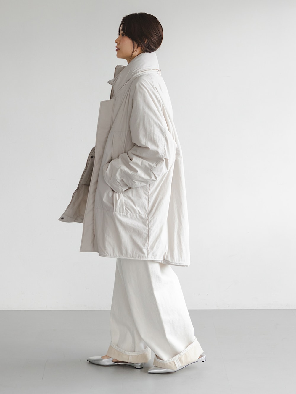 ホワイト系のダウンジャケット/コート、グレー系のニット/セーター、ホワイト系のデニムパンツを着用したレディースの秋コーディネートの2枚目の写真