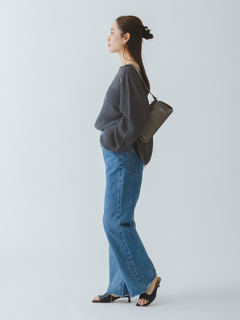 グレー系のニット/セーター、ブルー系のデニムパンツ、ブラック系のサンダルを着用したレディースの春コーディネートの3枚目の写真