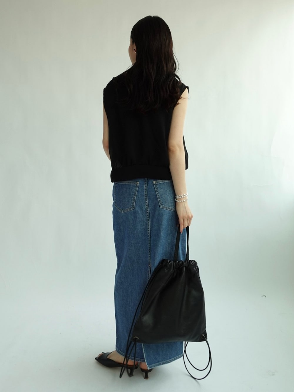 ブラック系のベスト、ブルー系のデニムスカートを着用したレディースの夏コーディネートの2枚目の写真