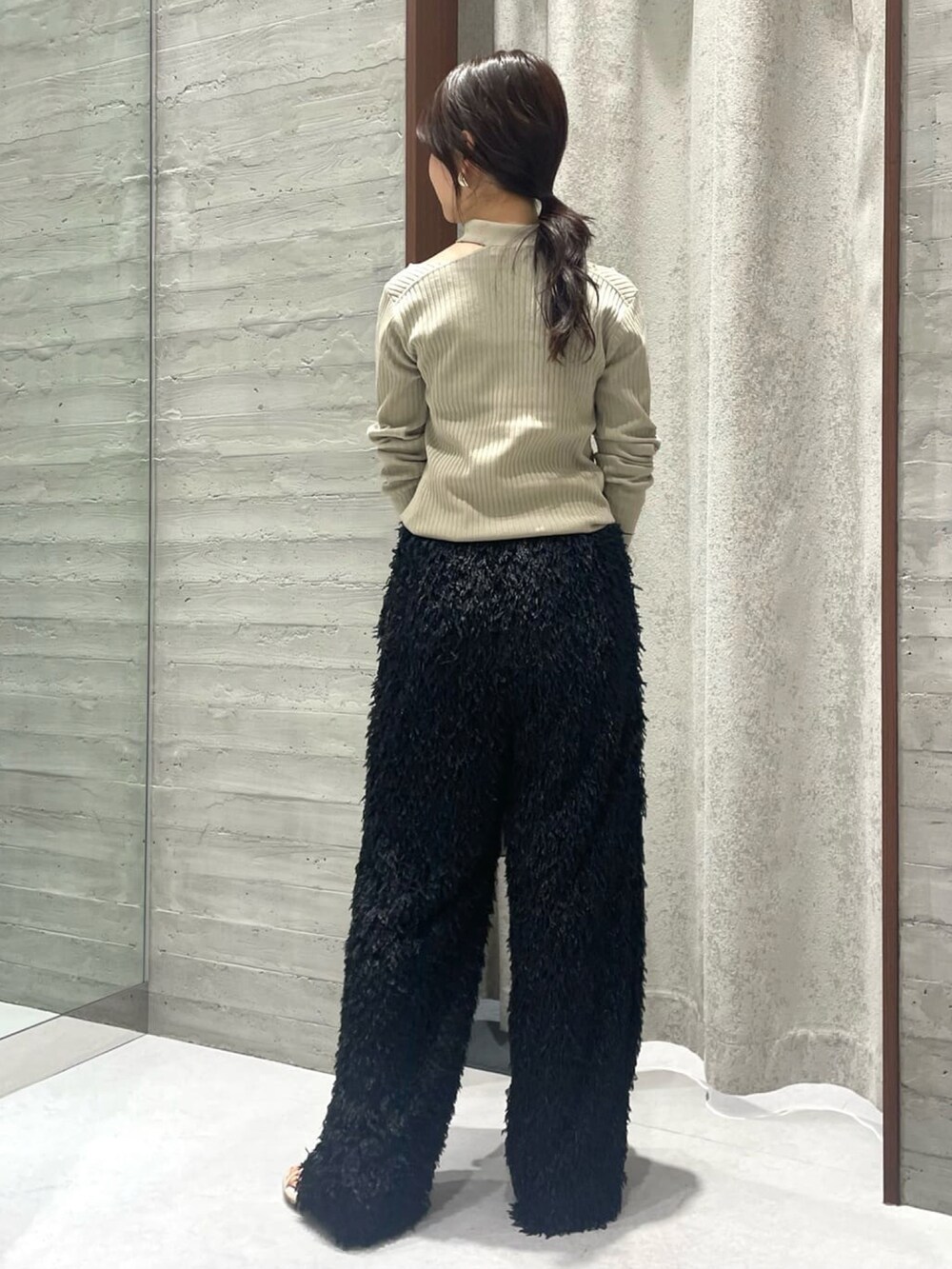 グリーン系のニット/セーター、ブラック系のスラックス、ベージュ系のショルダーバッグを着用したレディースの夏コーディネートの2枚目の写真