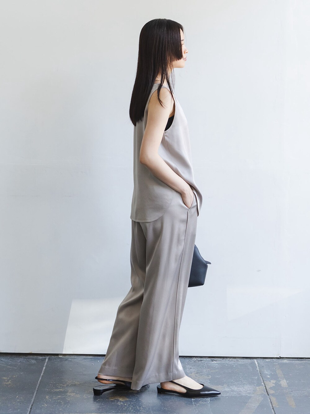 グレー系のタンクトップ、グレー系のスラックス、ブラック系のショルダーバッグを着用したレディースの秋コーディネートの2枚目の写真