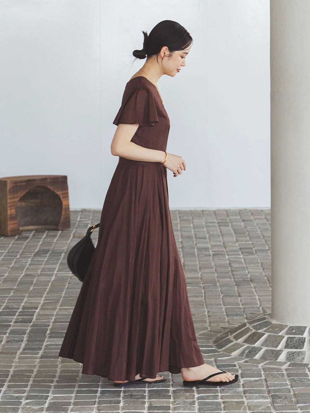 ブラウン系のワンピース、ブラック系のハンドバッグ、ブラック系のサンダルを着用したレディースの夏コーディネートの2枚目の写真