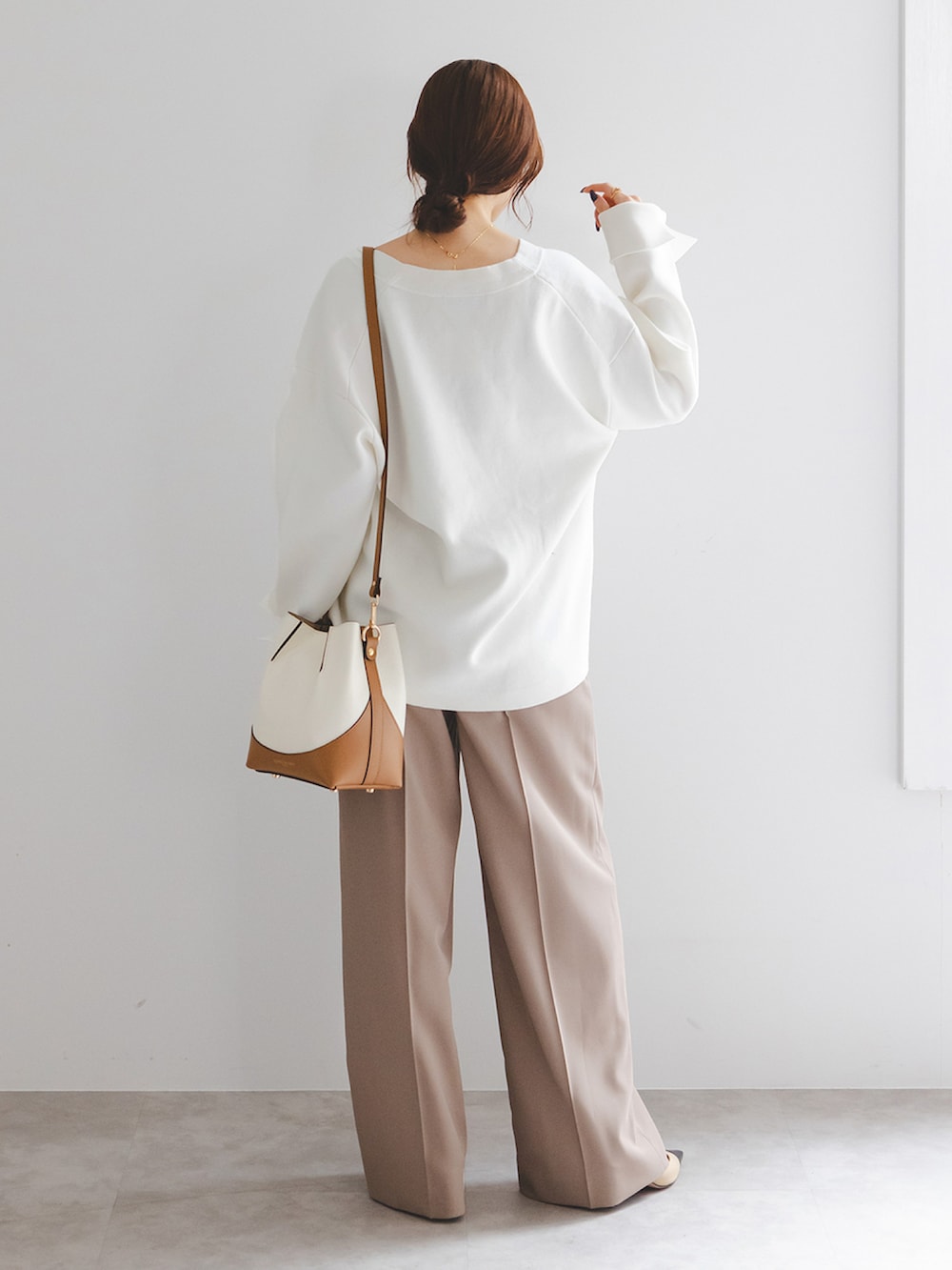 ホワイト系のカーディガン/ボレロ、ブラウン系のスラックス、ホワイト系のショルダーバッグを着用したレディースの春コーディネートの2枚目の写真