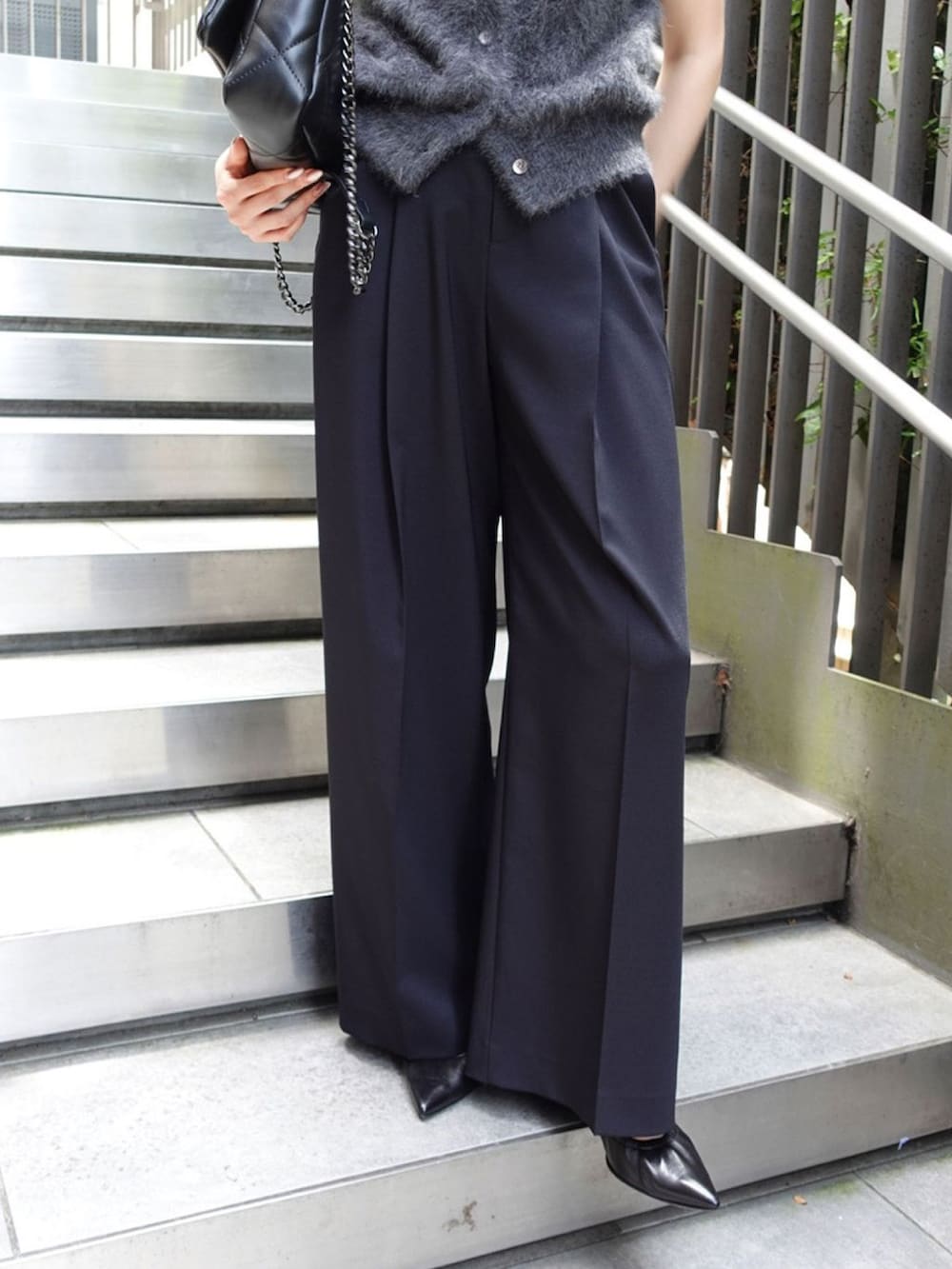 グレー系のベスト、ブルー系のスラックス、ブラック系のパンプスを着用したレディースの秋コーディネートの4枚目の写真