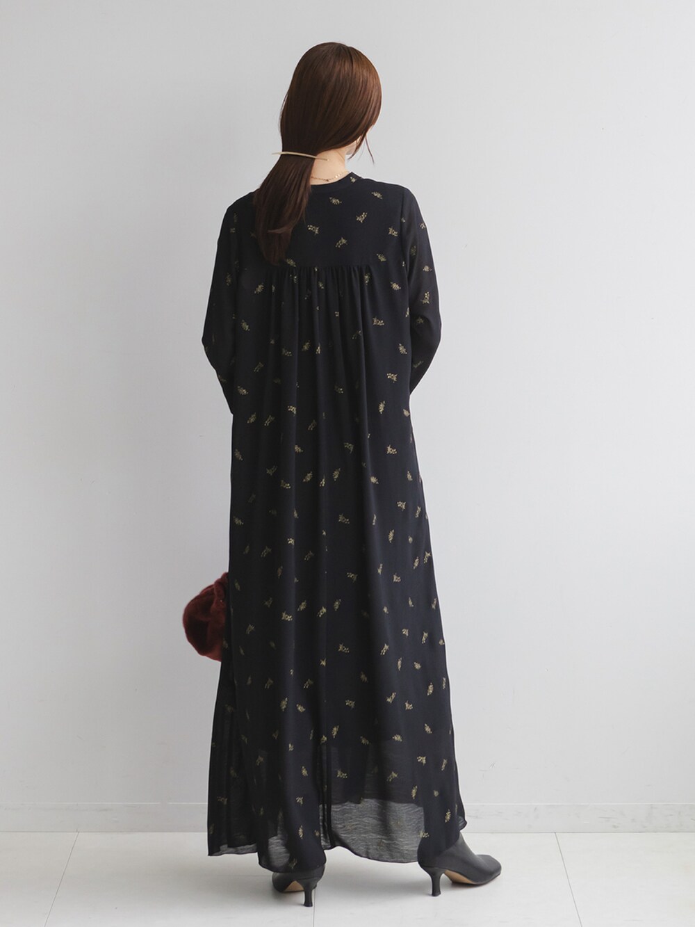 ブラック系のワンピース、レッド系のハンドバッグ、ブラック系のブーツを着用したレディースの冬コーディネートの3枚目の写真