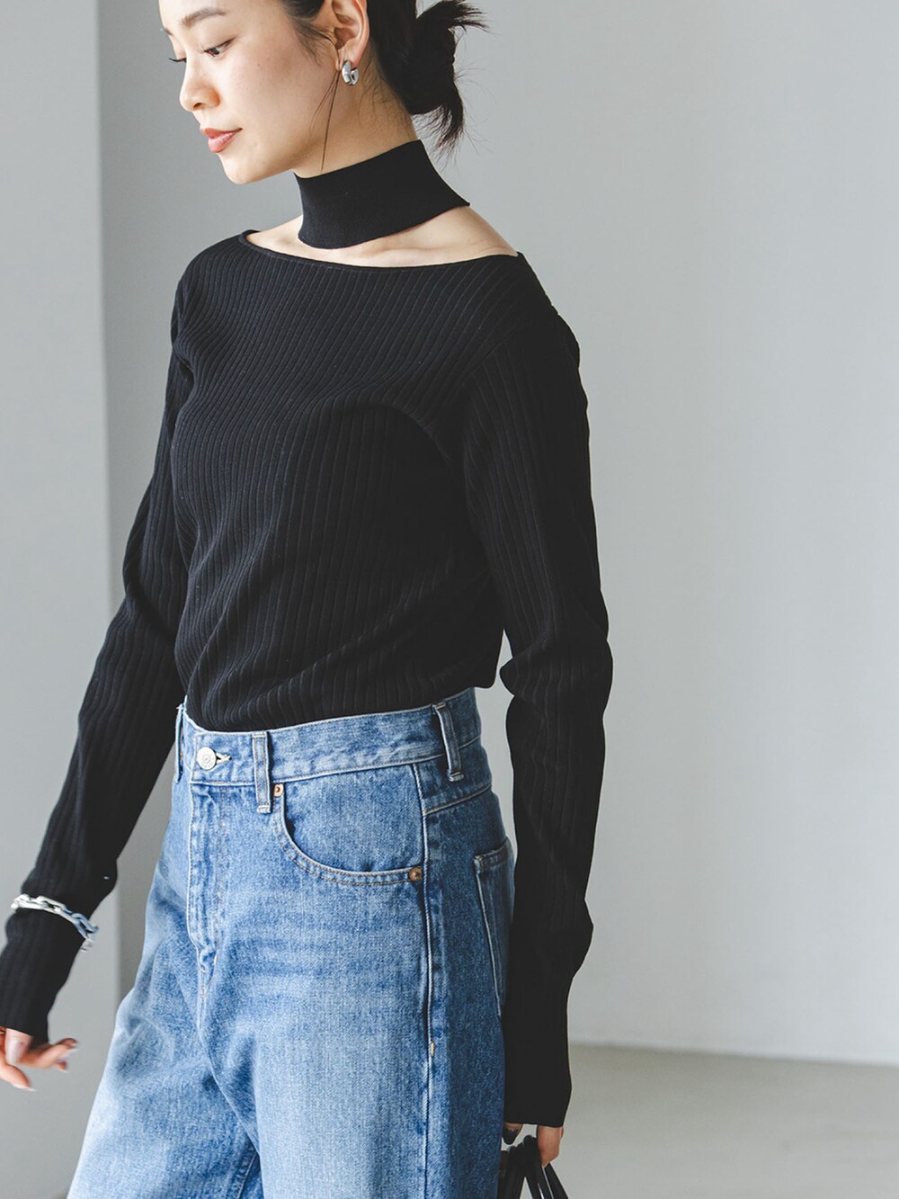 ブラック系のニット/セーター、ブルー系のデニムパンツを着用したレディースの夏コーディネートの3枚目の写真