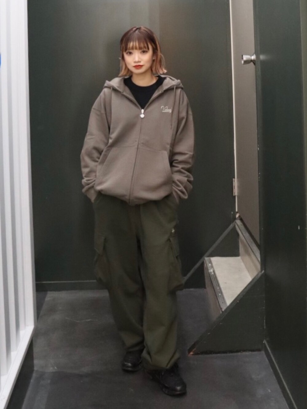 グレー系のパーカー、グリーン系のスウェットパンツ、ブラック系のTシャツ/カットソーを着用したレディースの秋コーディネートの3枚目の写真