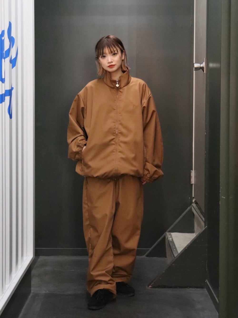 ブラウン系のナイロンジャケット、ブラウン系のその他パンツを着用したレディースの秋コーディネートの3枚目の写真