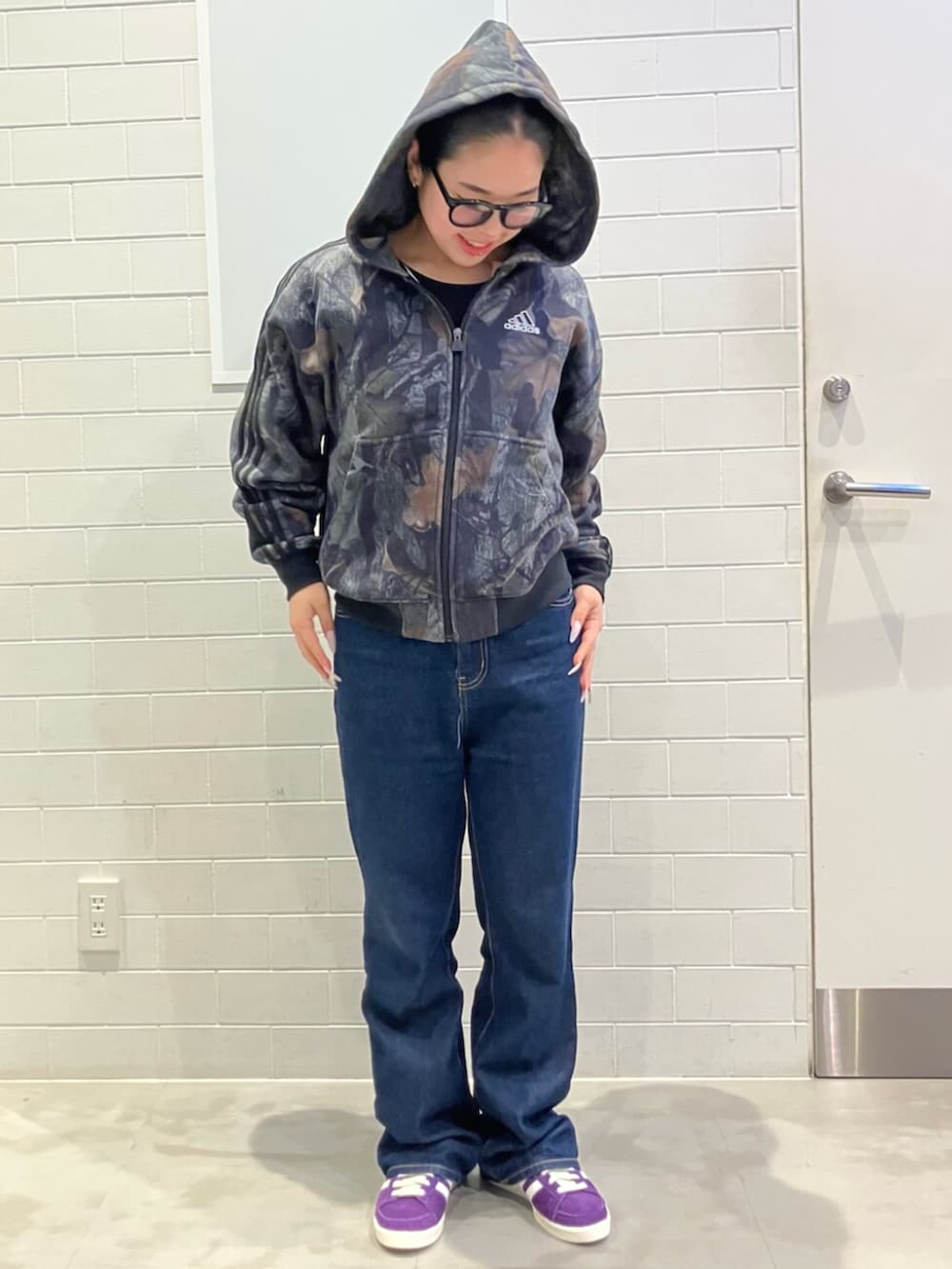 ブラック系のパーカー、パープル系のスニーカーを着用したレディースの秋コーディネートの3枚目の写真