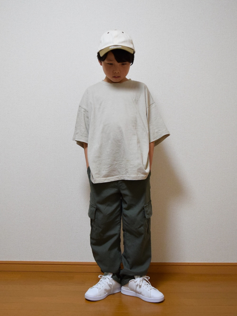 グリーン系のカーゴパンツ、ホワイト系のスニーカー、ベージュ系のTシャツ/カットソーを着用したキッズの春コーディネートの2枚目の写真