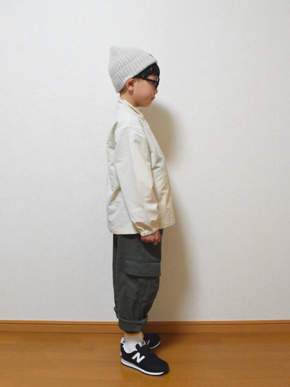 グリーン系のカーゴパンツ、ブラック系のスニーカー、ホワイト系のナイロンジャケットを着用したキッズの冬コーディネートの2枚目の写真