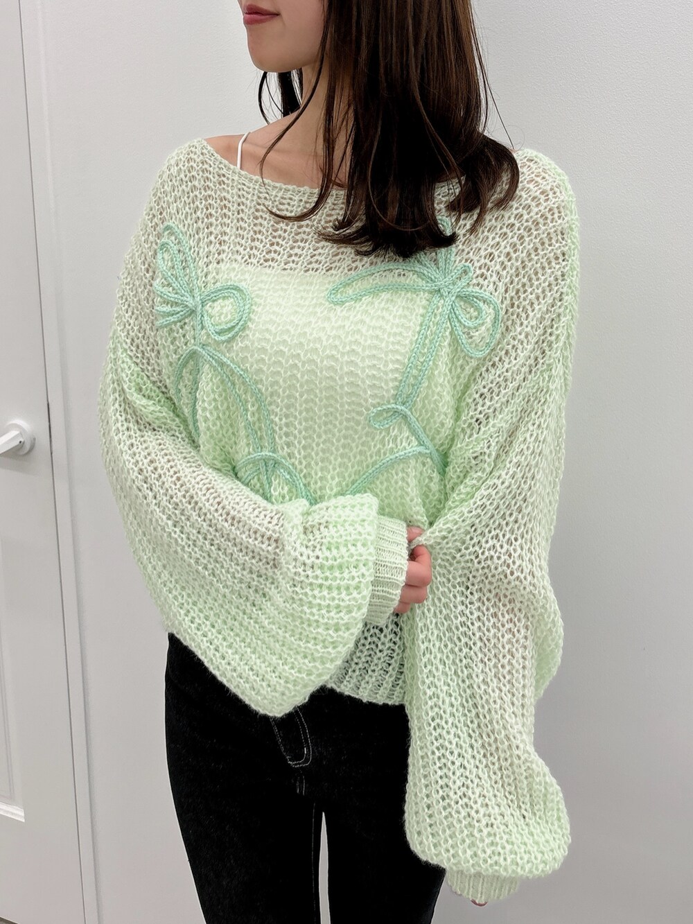 ブラック系のデニムパンツ、グリーン系のニット/セーター、ブラック系のパンプスを着用したレディースの夏コーディネートの6枚目の写真