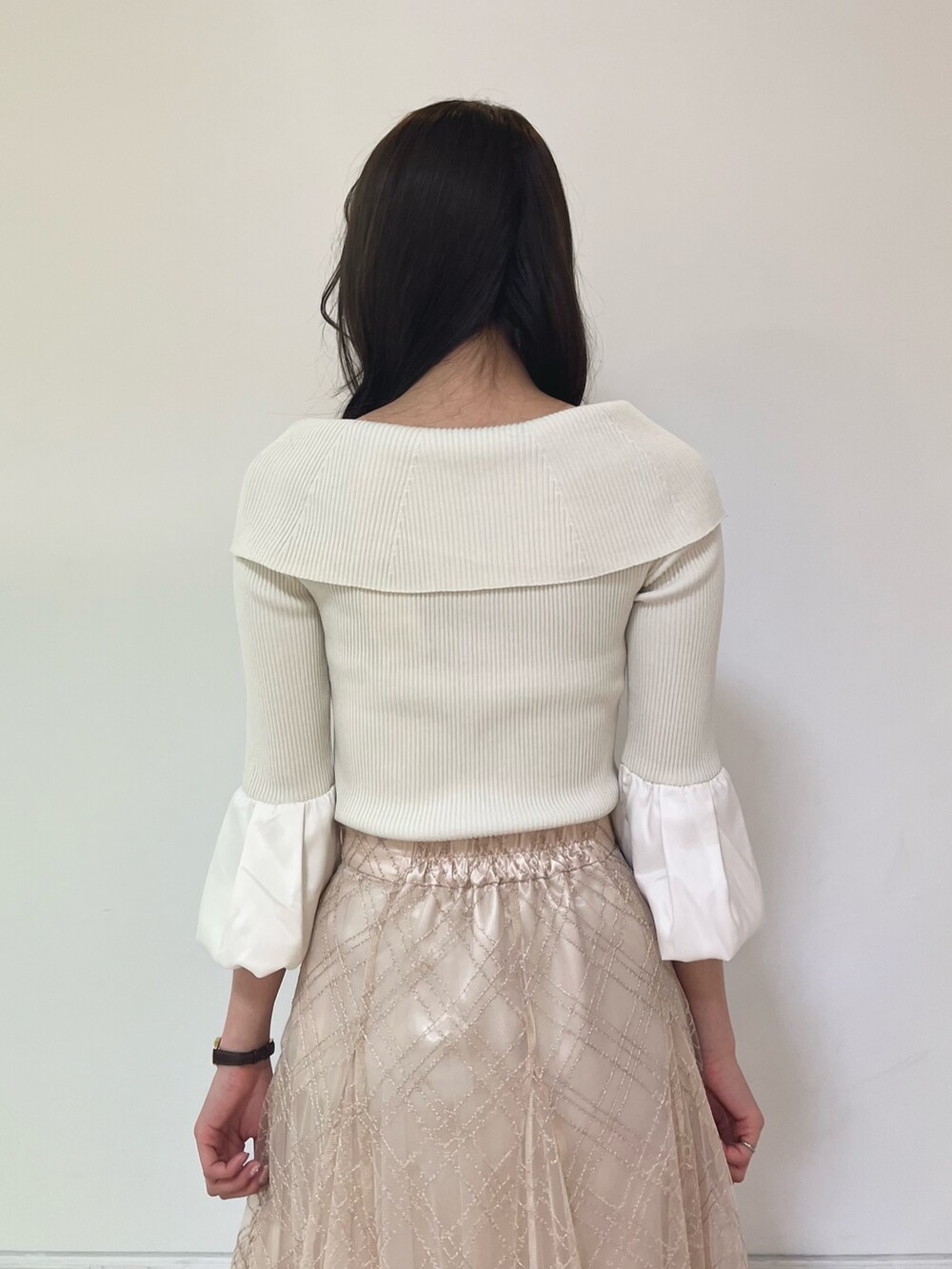 ベージュ系のスカート、ゴールド系のパンプス、ホワイト系のニット/セーターを着用したレディースの春コーディネートの5枚目の写真