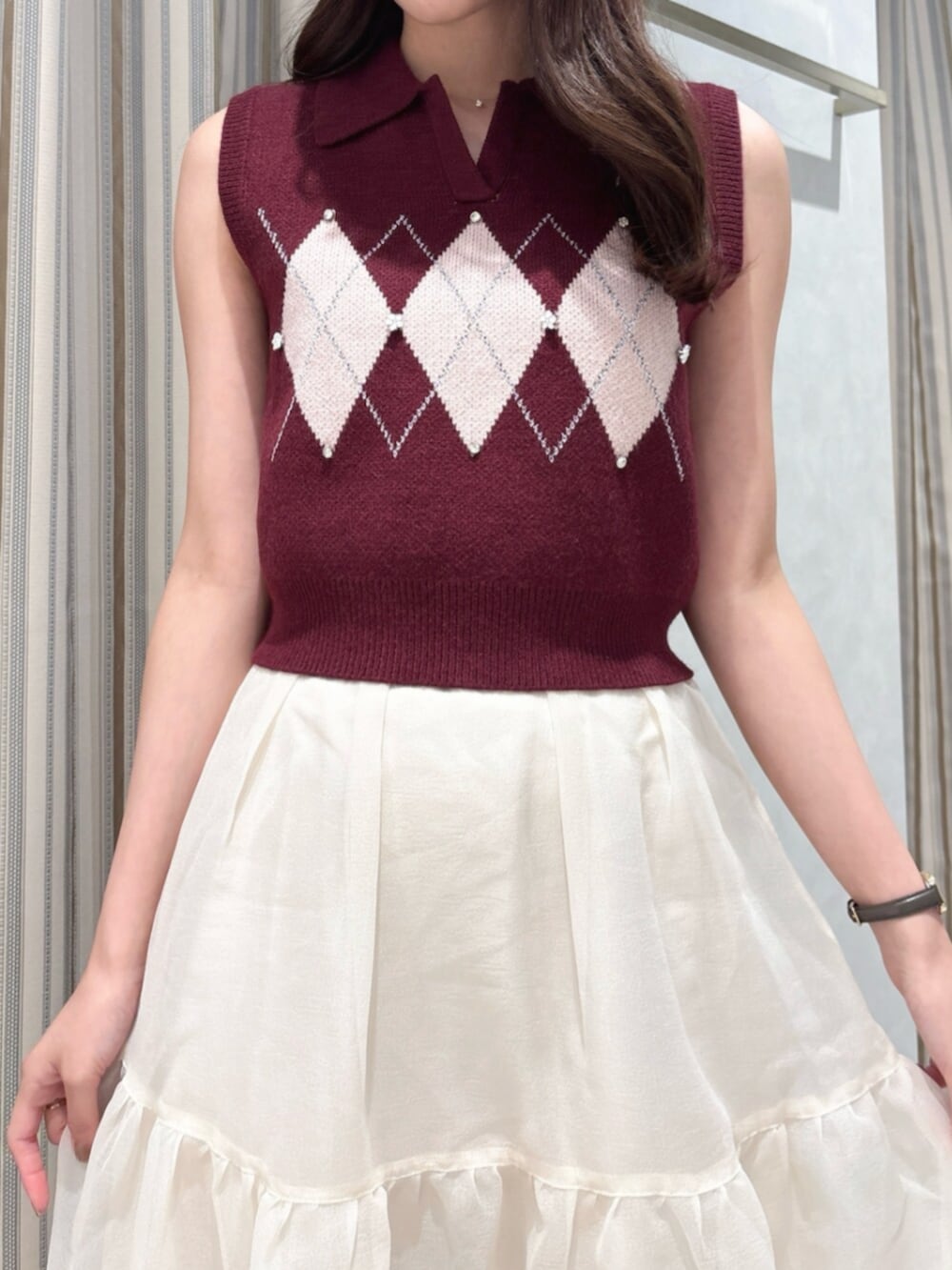 レッド系のニット/セーター、ベージュ系のスカート、ブラウン系のショルダーバッグを着用したレディースの秋コーディネートの6枚目の写真