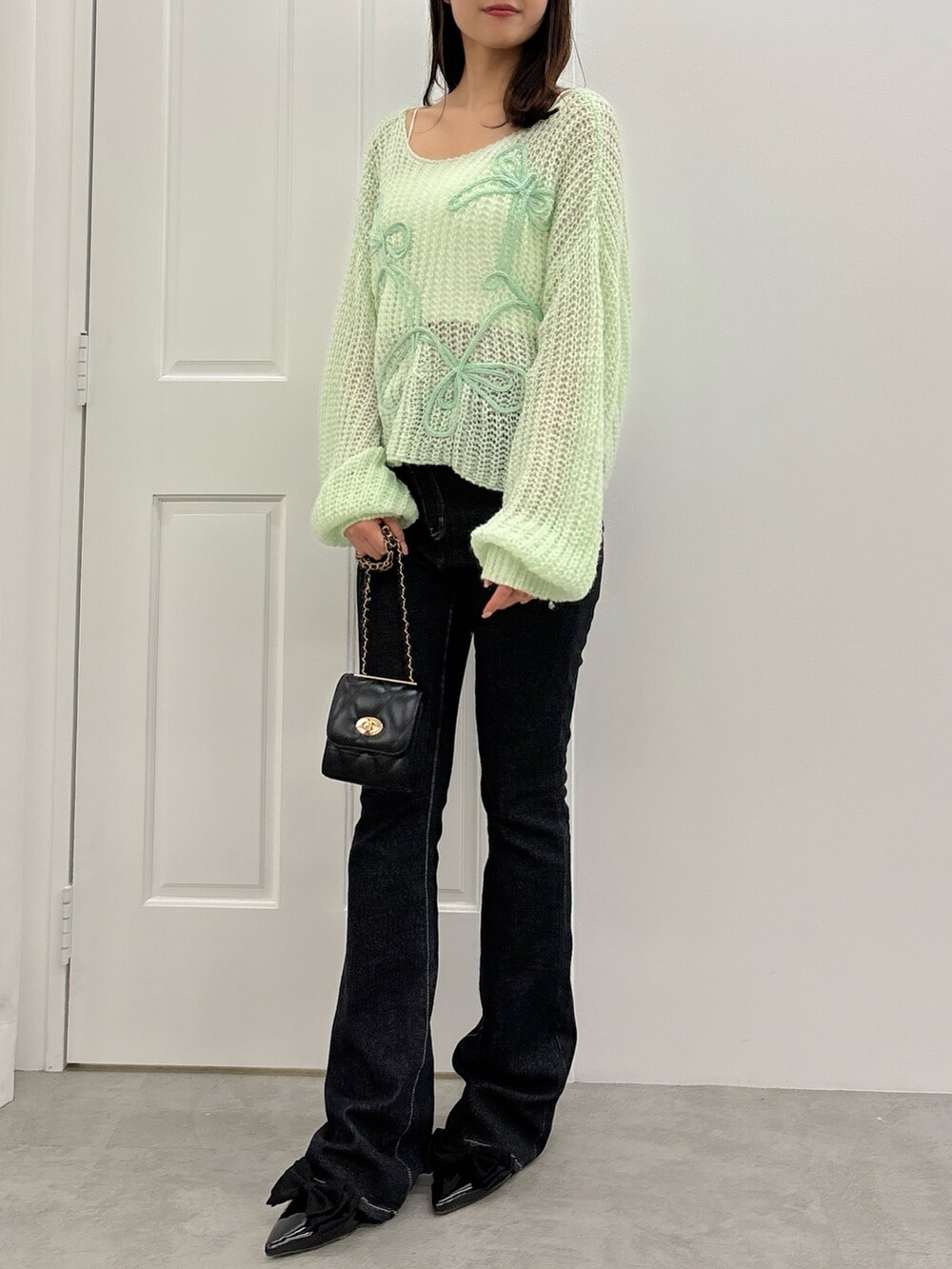 ブラック系のデニムパンツ、グリーン系のニット/セーター、ブラック系のパンプスを着用したレディースの夏コーディネートの2枚目の写真