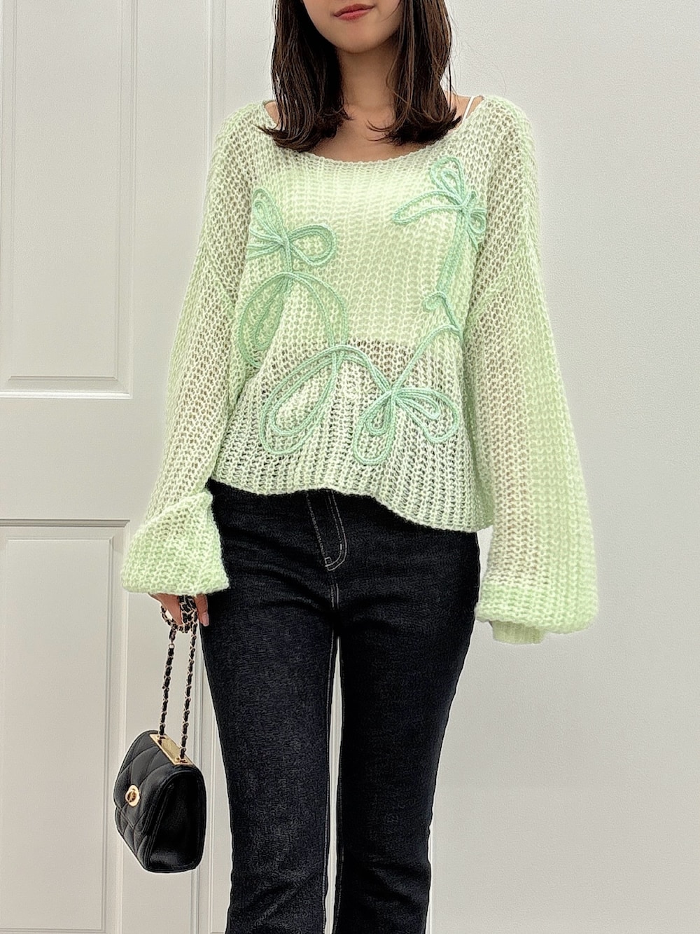 ブラック系のデニムパンツ、グリーン系のニット/セーター、ブラック系のパンプスを着用したレディースの夏コーディネートの4枚目の写真