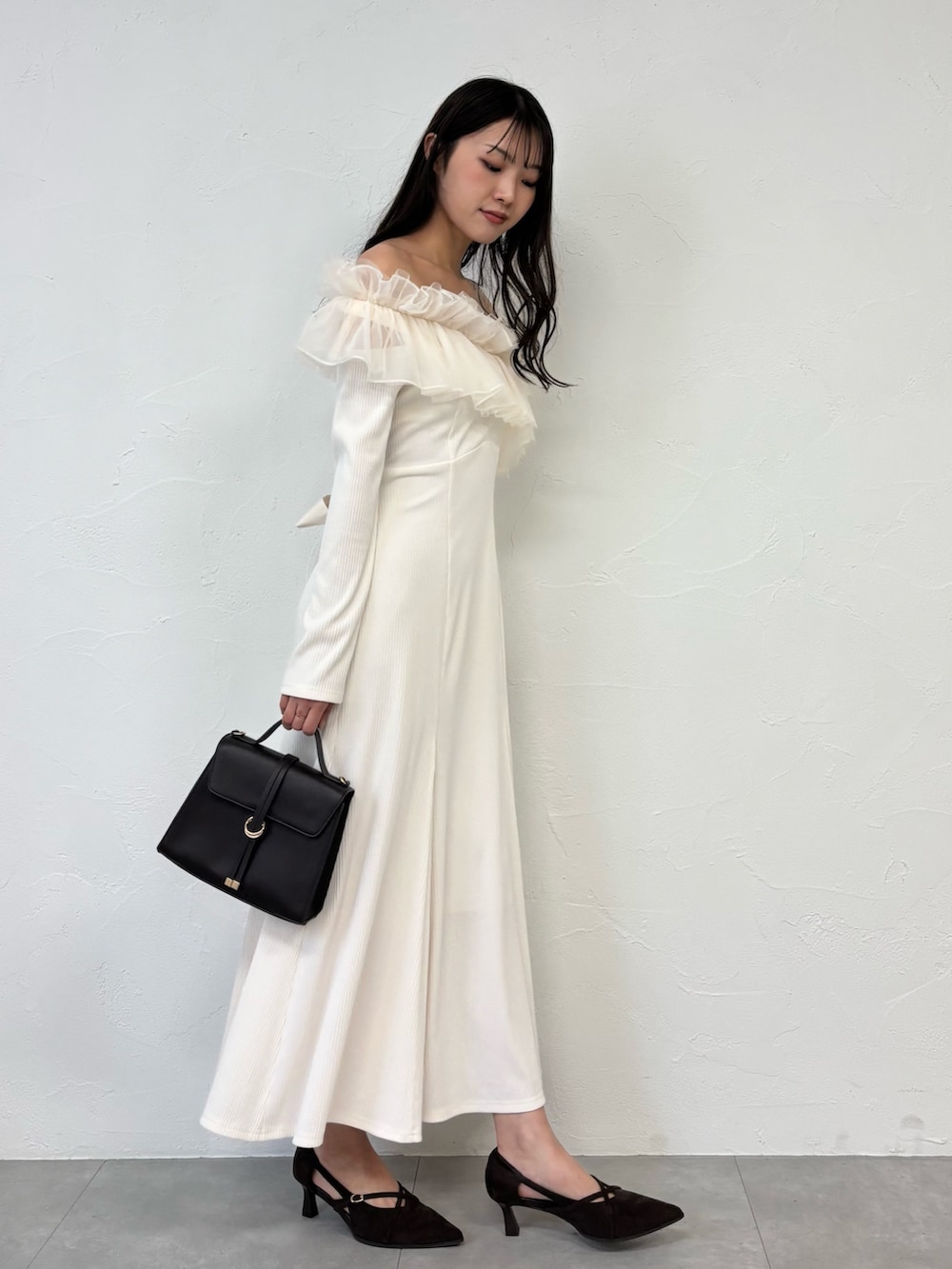 ブラウン系のショルダーバッグ、ブラウン系のパンプス、ホワイト系のワンピースを着用したレディースの秋コーディネートの5枚目の写真