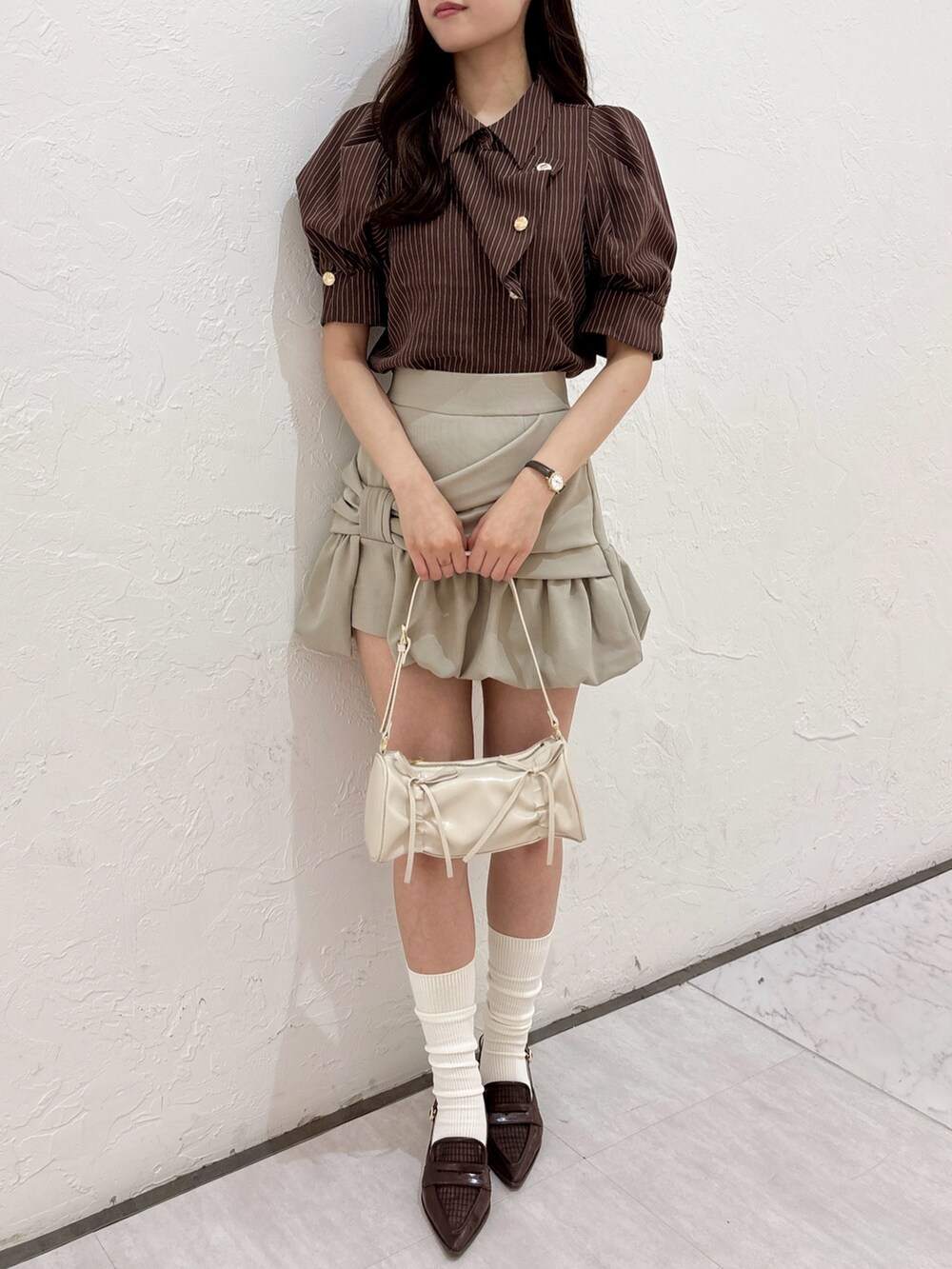 ブラウン系のシャツ/ブラウス、ベージュ系のスカート、ブラウン系のローファーを着用したレディースの夏コーディネートの2枚目の写真