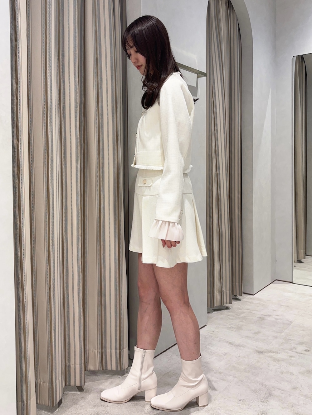 ホワイト系のノーカラージャケット、ホワイト系のスカート、ホワイト系のブーツを着用したレディースの春コーディネートの5枚目の写真