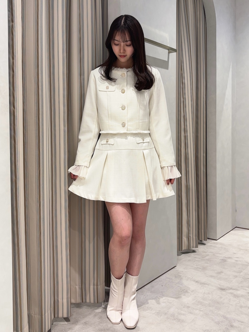 ホワイト系のノーカラージャケット、ホワイト系のスカート、ホワイト系のブーツを着用したレディースの春コーディネートの4枚目の写真