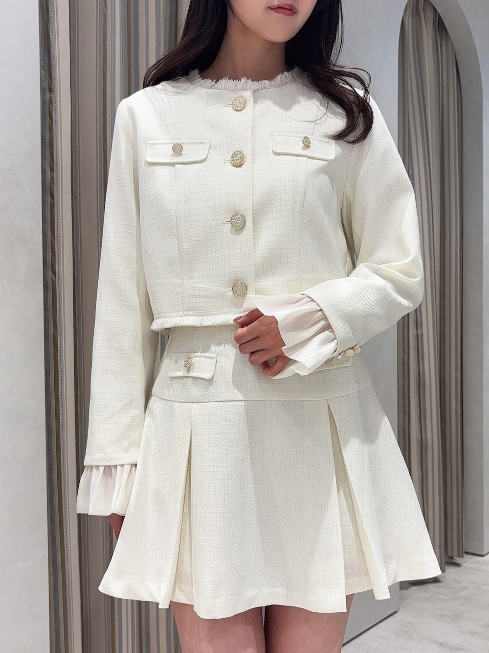 ホワイト系のノーカラージャケット、ホワイト系のスカート、ホワイト系のブーツを着用したレディースの春コーディネートの7枚目の写真