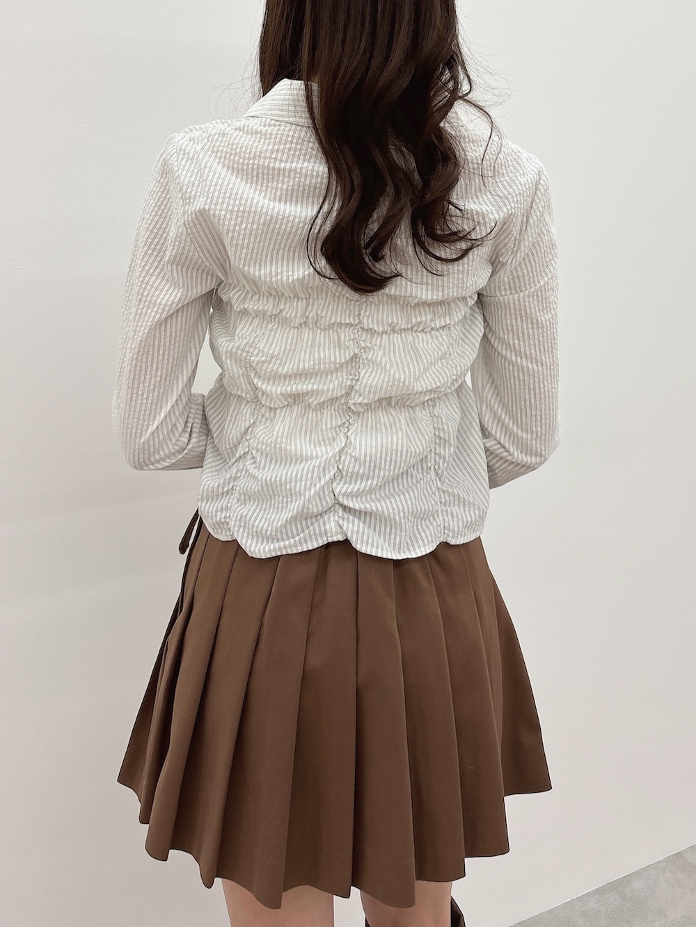 ブルー系のシャツ/ブラウス、イエロー系のスカート、ブラウン系のブーツを着用したレディースの春コーディネートの6枚目の写真