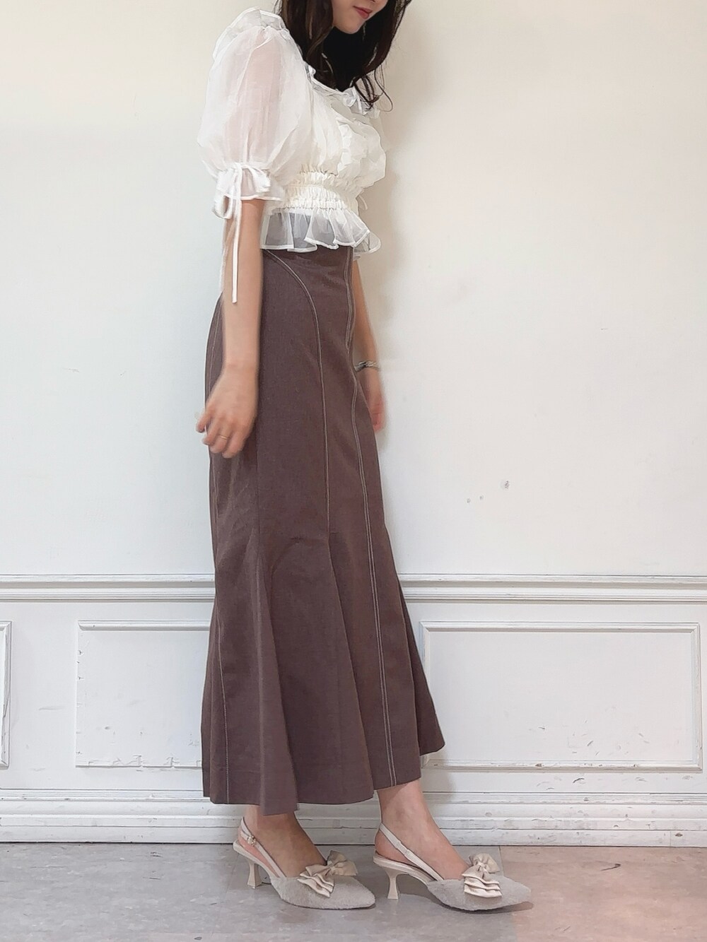 ブラウン系のスカート、ホワイト系のシャツ/ブラウス、ベージュ系のパンプスを着用したレディースの秋コーディネートの2枚目の写真