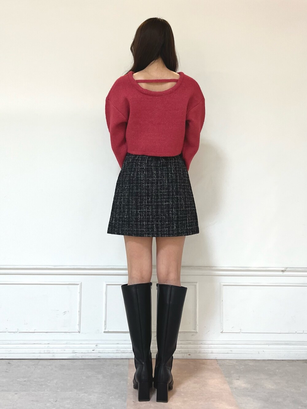 ブラック系のブーツ、ブラック系のスカート、レッド系のニット/セーターを着用したレディースの秋コーディネートの2枚目の写真