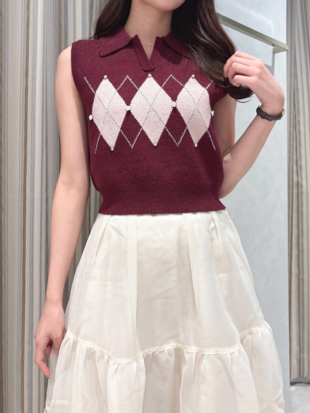 レッド系のニット/セーター、ベージュ系のスカート、ブラウン系のショルダーバッグを着用したレディースの秋コーディネートの5枚目の写真