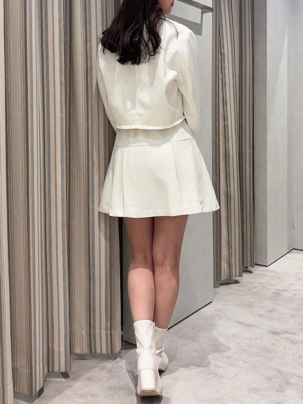 ホワイト系のノーカラージャケット、ホワイト系のスカート、ホワイト系のブーツを着用したレディースの春コーディネートの6枚目の写真