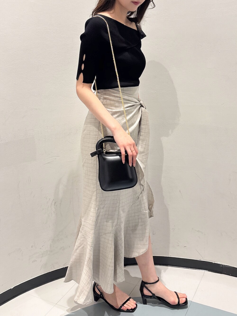 ブラック系のニット/セーター、ベージュ系のスカート、ブラック系のサンダルを着用したレディースの夏コーディネートの2枚目の写真