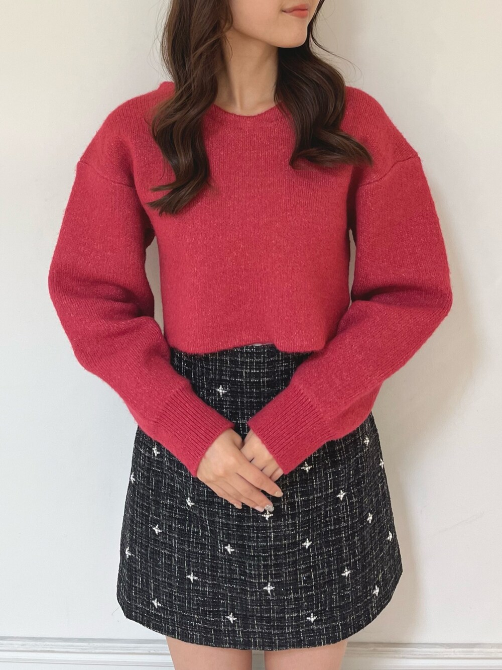 ブラック系のブーツ、ブラック系のスカート、レッド系のニット/セーターを着用したレディースの秋コーディネートの3枚目の写真