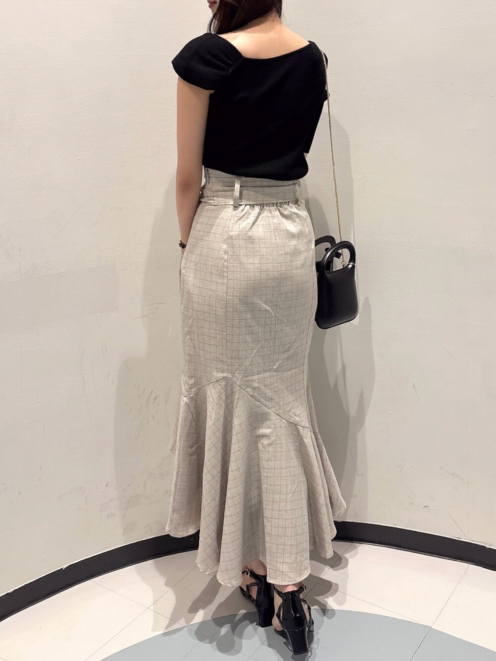 ブラック系のニット/セーター、ベージュ系のスカート、ブラック系のサンダルを着用したレディースの夏コーディネートの3枚目の写真