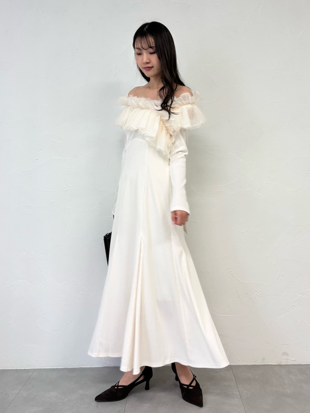 ブラウン系のショルダーバッグ、ブラウン系のパンプス、ホワイト系のワンピースを着用したレディースの秋コーディネートの4枚目の写真