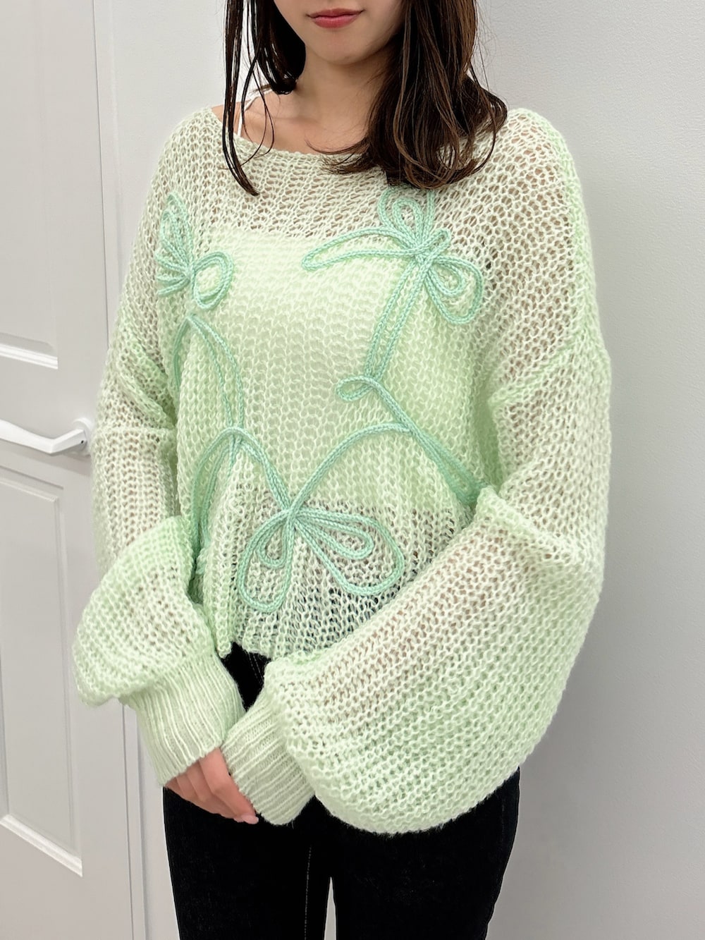 ブラック系のデニムパンツ、グリーン系のニット/セーター、ブラック系のパンプスを着用したレディースの夏コーディネートの5枚目の写真